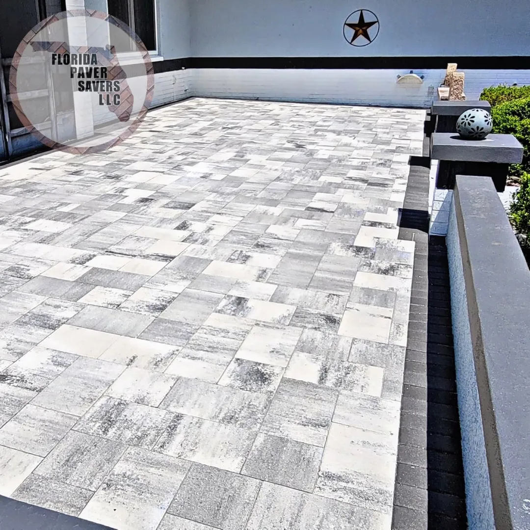Carefully laid pale paver patio with a dark border and matching retaining wall